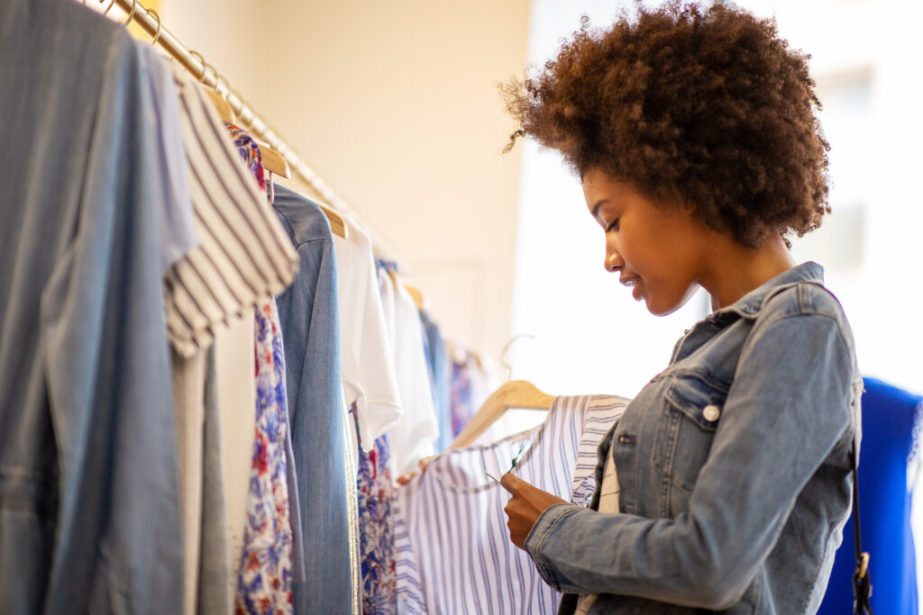 Side portrait of beautiful young black woman with afro shopping for clothes in store that do not release microfibers into the environment